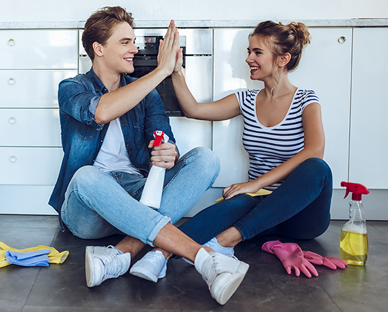 two people high-fiving each other and cleaning products on the floor